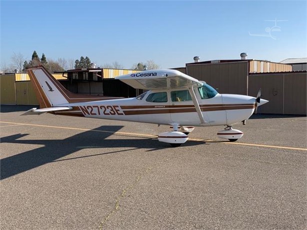 Right-side exterior profile of Cessna 172N N2723E parked on the ramp near the hangars.